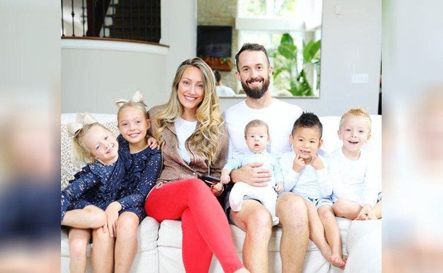 Myka, James, and their five children, including Huxley, sitting on the couch 