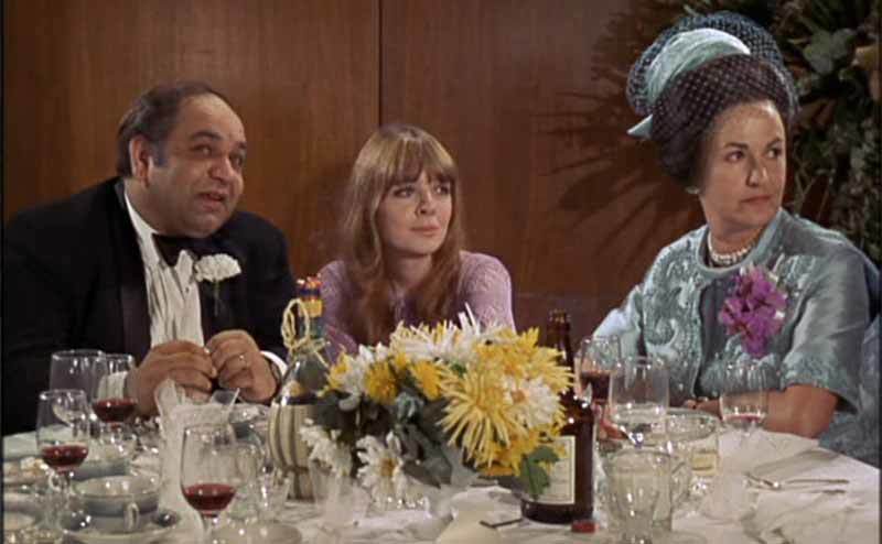 Diane Keaton with two others sitting at a round table during a wedding in a scene from Lovers and Other Strangers 