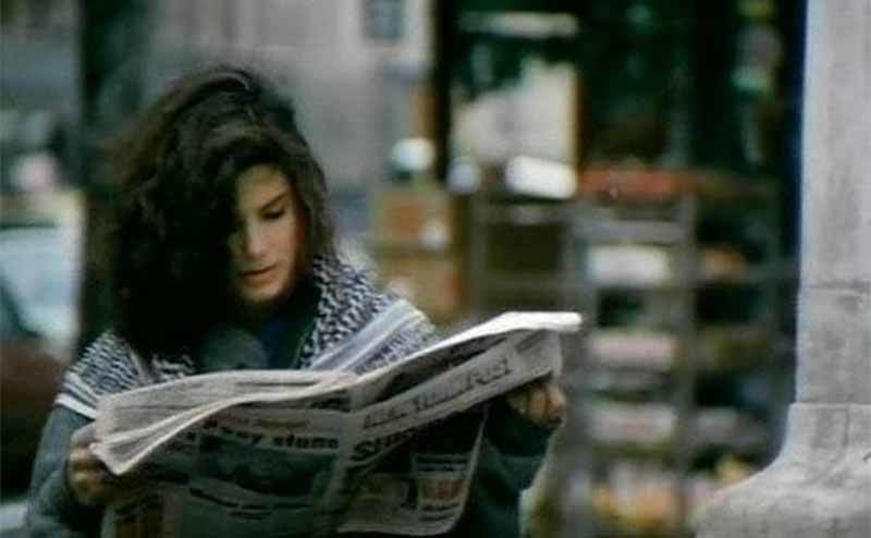 Sandra Bullock reading a newspaper outside in the film Hangmen 
