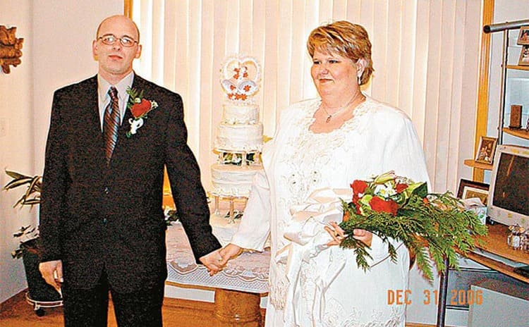 Jeff and Penny in front of their wedding cake 