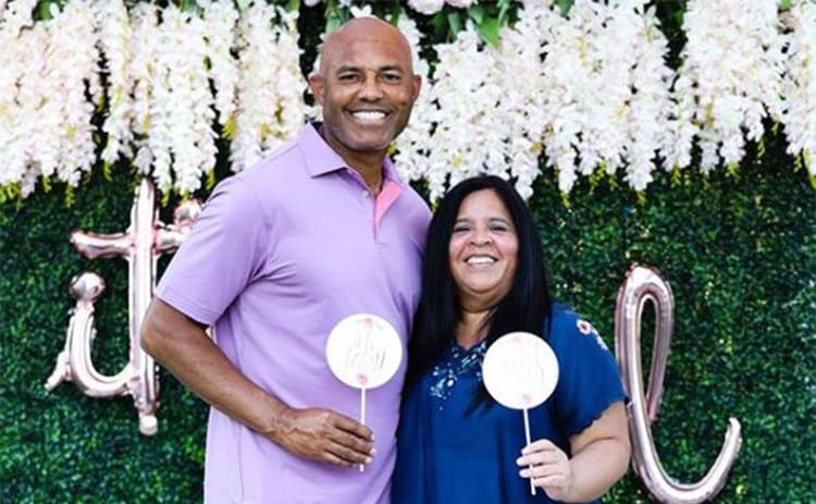 Mariano Rivera and Clara Rivera posing in front of a wall of green and white flowers 