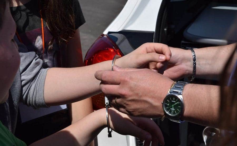 A woman having handcuffs placed on her arms