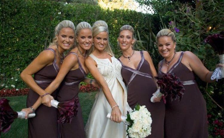 Erica in her wedding dress with her sisters to her left and bridesmaids to her right 