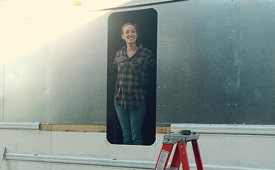 Rachel standing inside of an empty space where they will put a window in 
