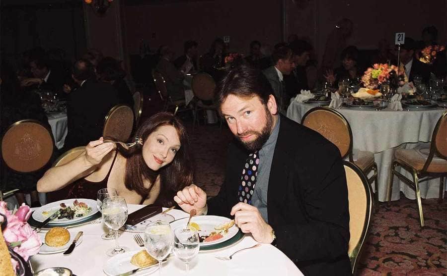 Amy Yasbeck and John Ritter at a dinner table together circa 1999