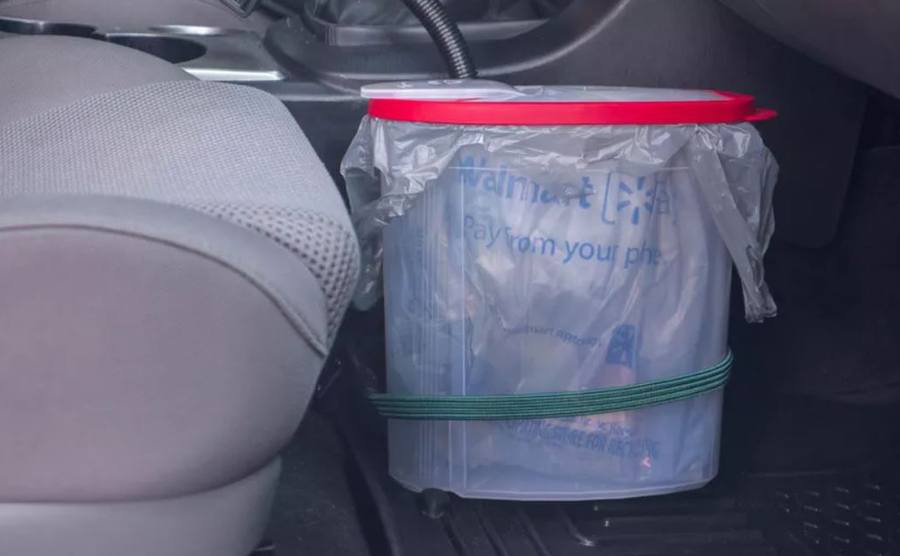 A cereal box next to the passenger’s seat with a plastic bag in it 