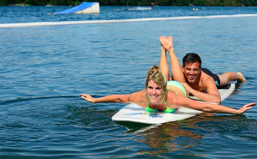 A couple lying on a large paddle board in the ocean 