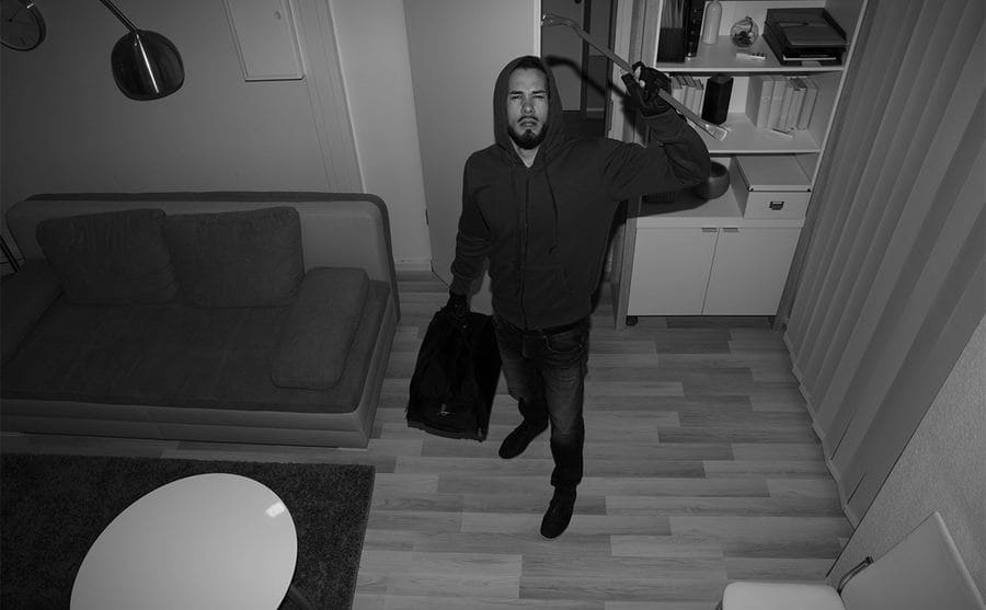 A confused robber looking up into a security camera 