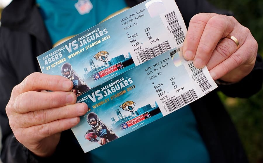 A man holding two tickets for the Jaguars and 49ers football game 