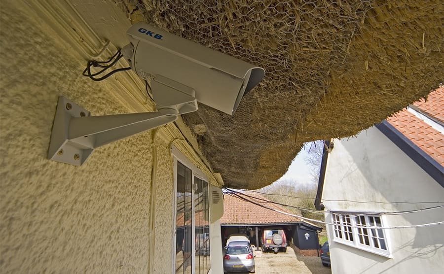 A security camera hooked up to the side of a house 