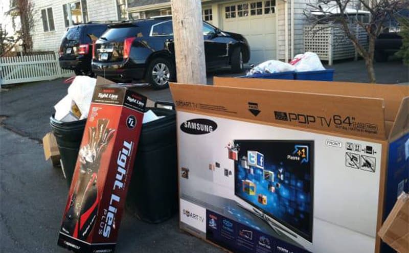 A smart TV and golf club box sitting by trash cans 