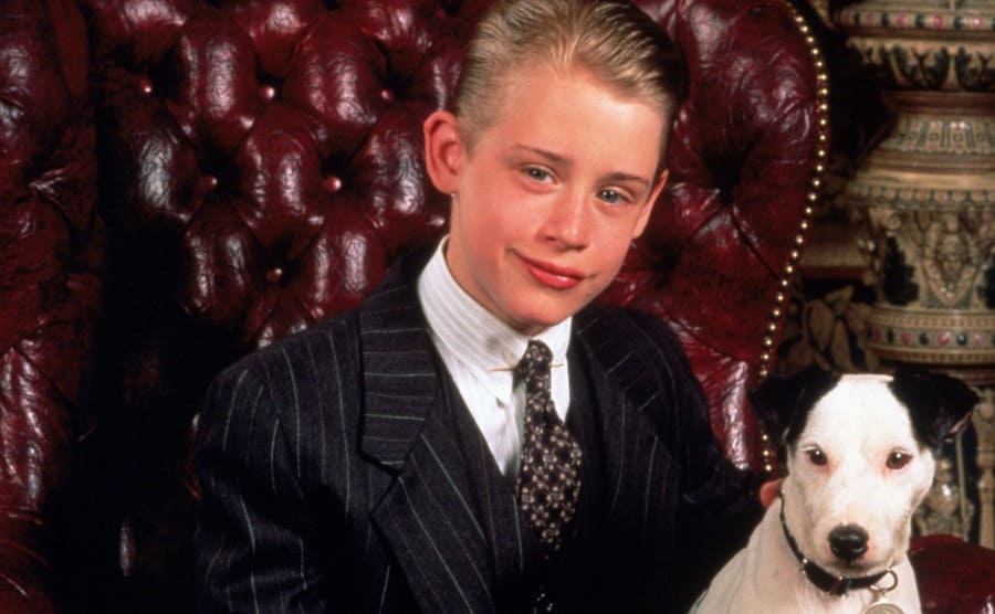 Macaulay Culkin y un perro sentado en una silla de cuero rojo
