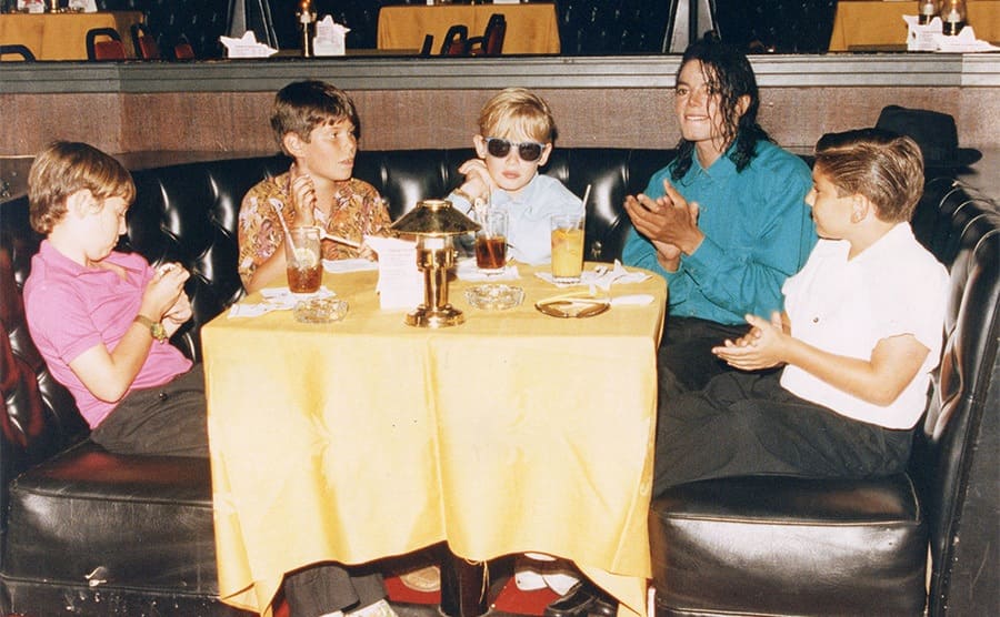 Macaulay Culkin y Michael Jackson con otros chicos tomando bebidas en una mesa en 1991
