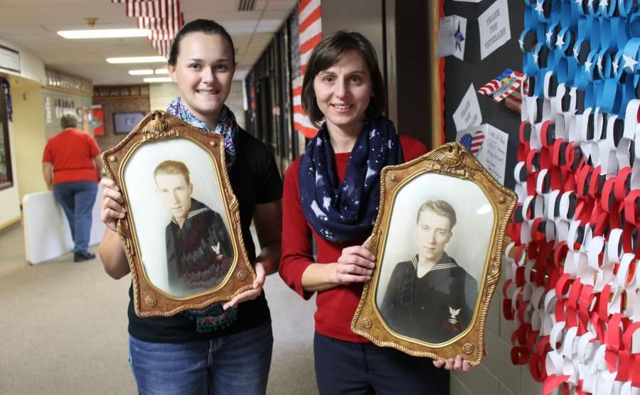 Taylor and Nichole holding photographs of the twins in the school hallway 