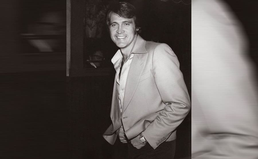 Young Lee Majors with hands in his pockets smiling