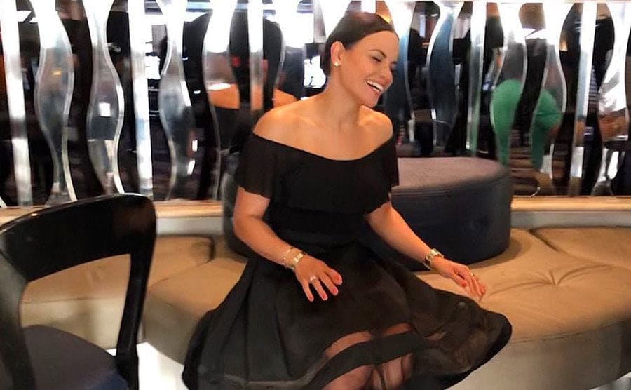 Samantha Sepulveda wearing a black dress, sitting and laughing