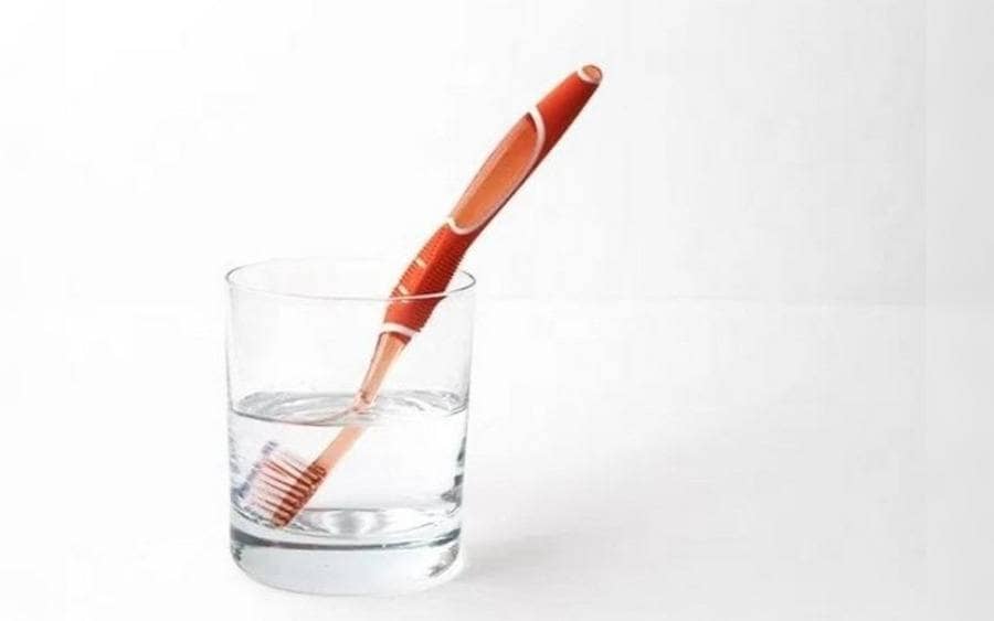  Cerdas de un cepillo de dientes dentro de un vaso con agua