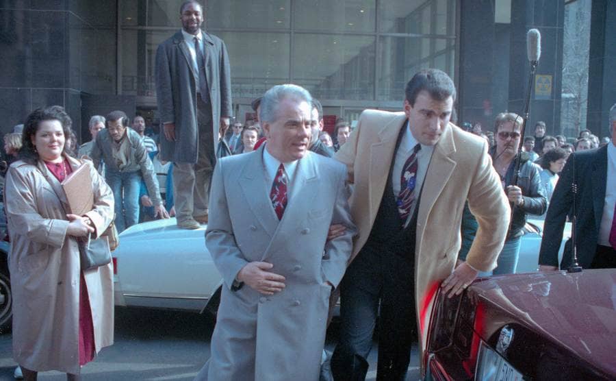 John Gotti is escorted by a man through the crowds outside the court 