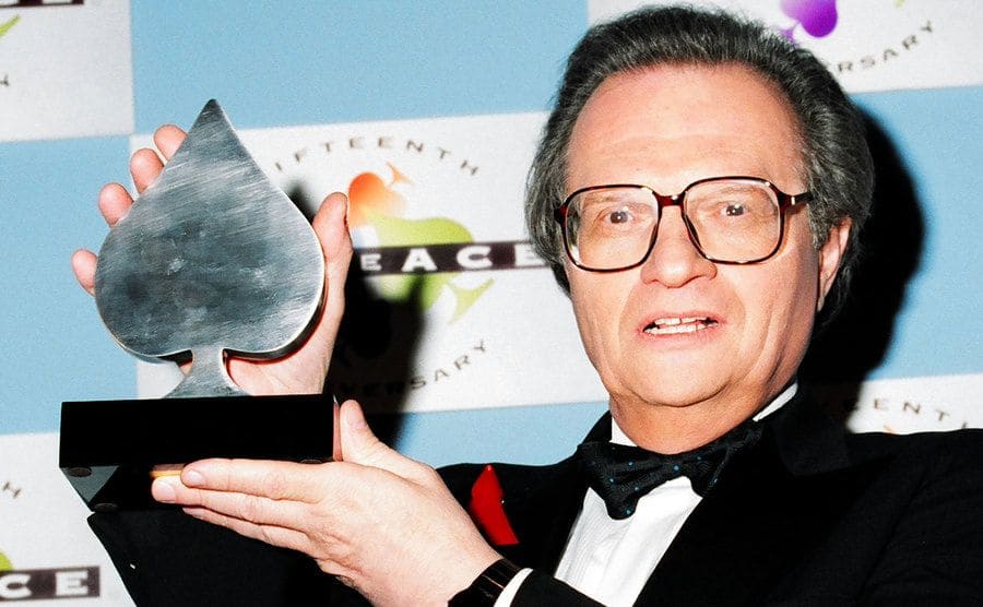 Larry King holding an award shaped as an Ace on the red carpet in 1994 