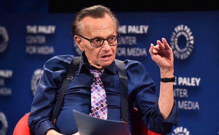 Larry King sitting in an armchair at a media events