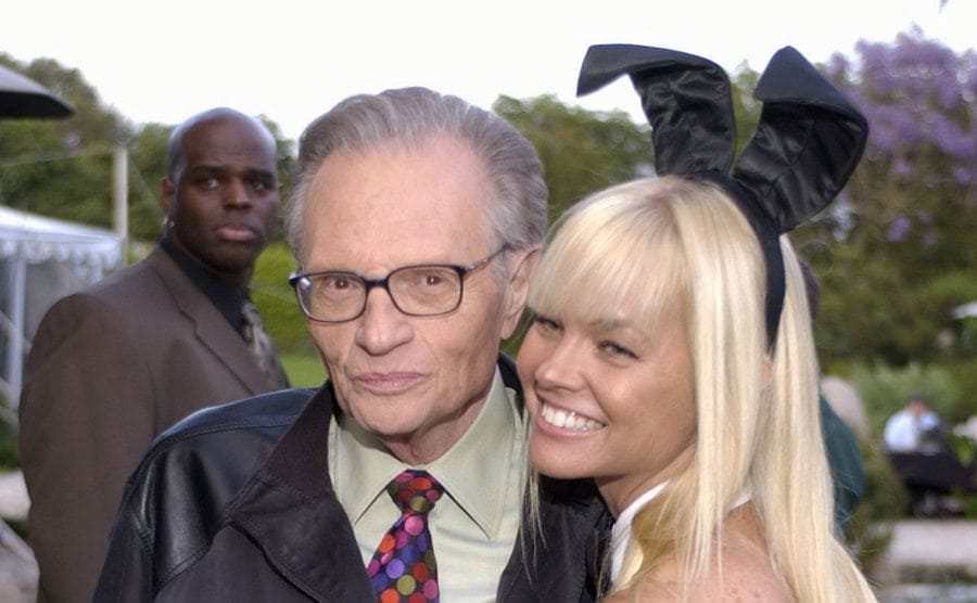 Larry King posing with a playboy playmate at the playboy mansion 