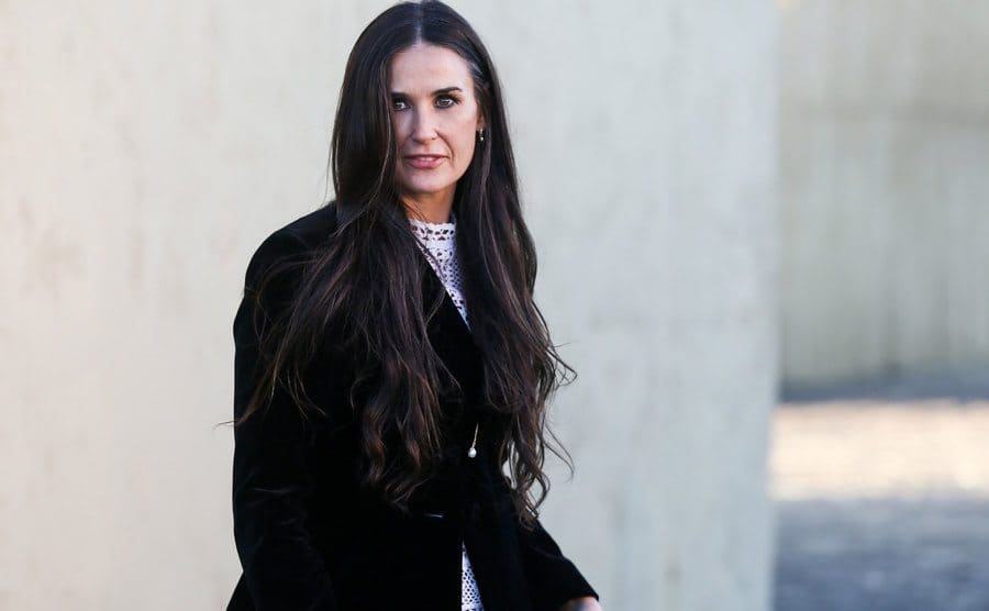 Demi Moore walking outside of a fashion show during the day 