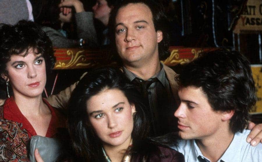 Elizabeth Perkins and James Belushi standing behind Demi Moore in a gaze while Rob Lowe looks lovingly at her 