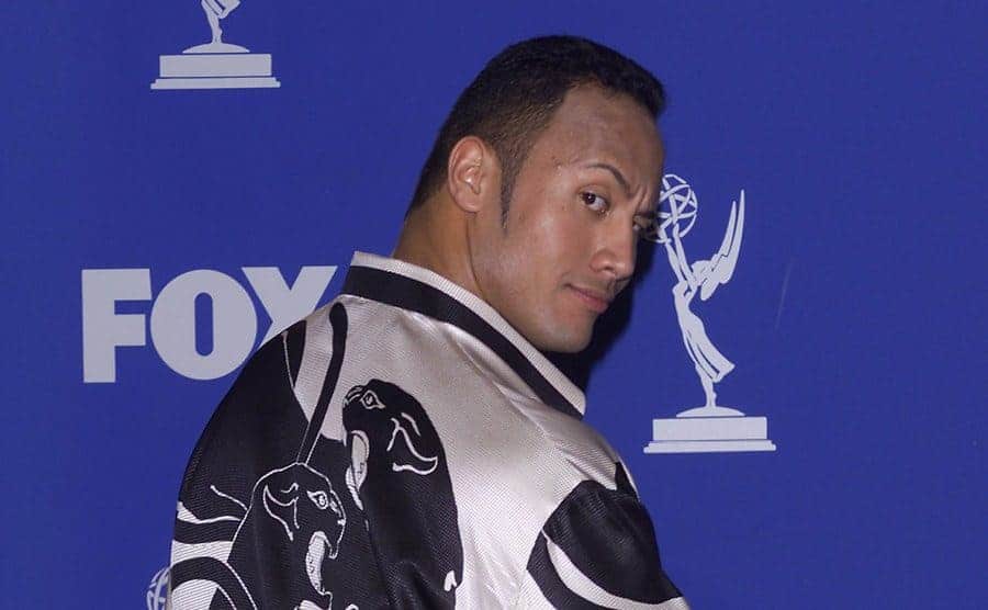 Dwayne Johnson posing with his back to the camera on the red carpet 