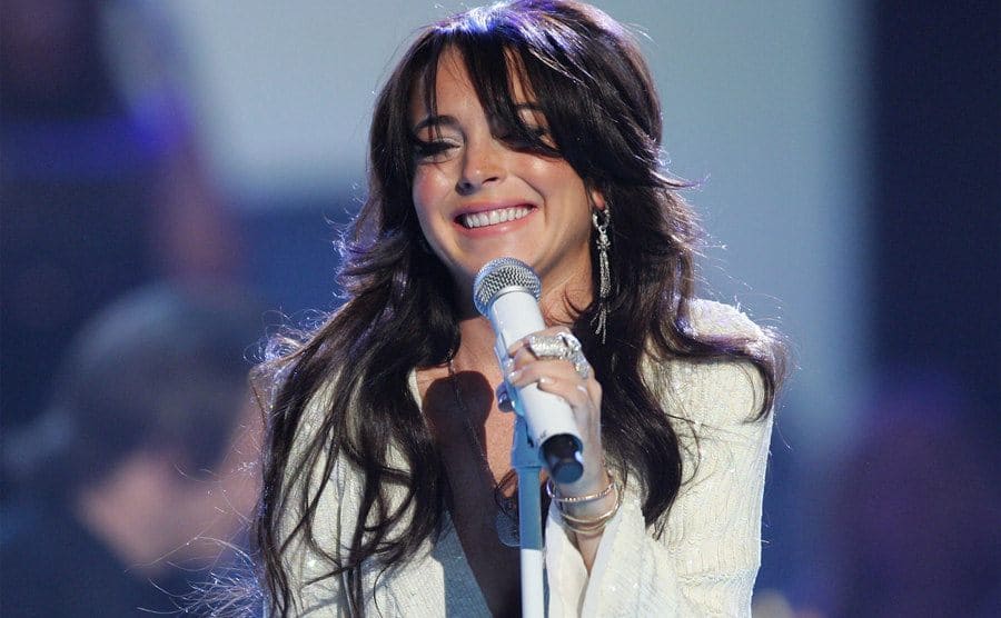 Lindsay Lohan performing wearing all white with a white microphone 