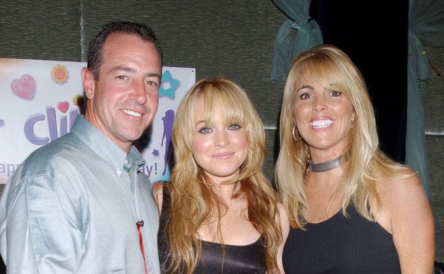 Lindsay Lohan posing on her birthday with her mother and father in 2003