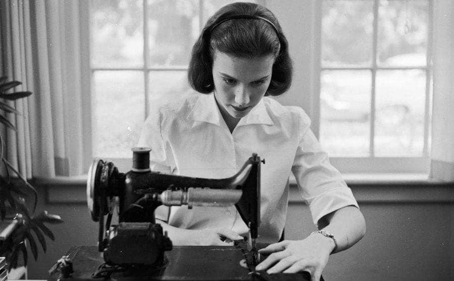 A teenage girl using a sewing machine in her home.