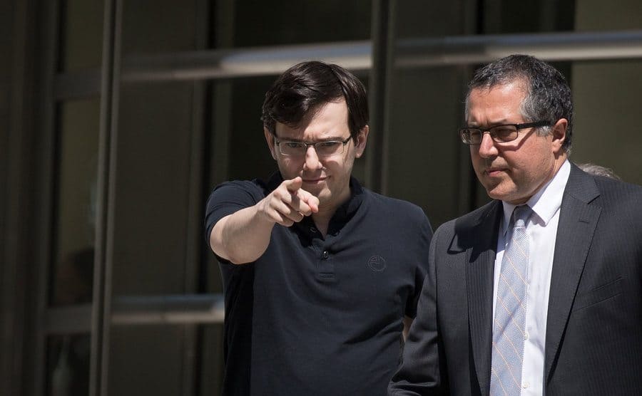 Shkreli walking out of court and pointing the finger at the camera. 