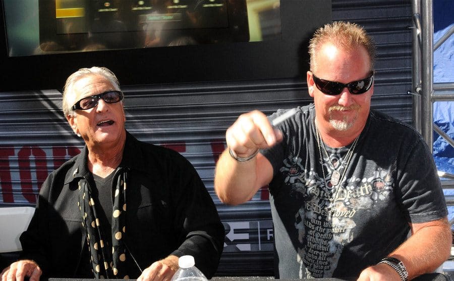 Reality stars Barry Weiss and Darrell Sheets signing autographs at a press event. 