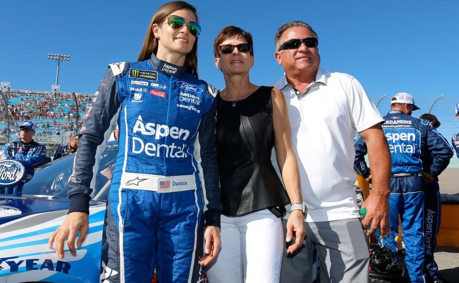 Danica Patrick with her parents posing near her racecar during a championship 