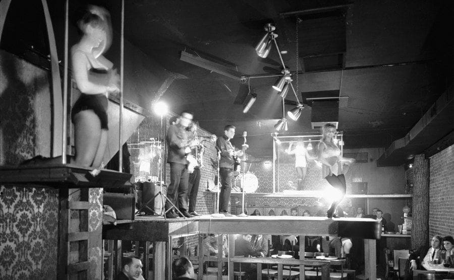 Go-Go dancers on elevated platforms entertaining customers at the club. 