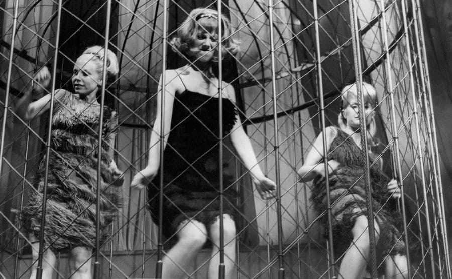 Three Go-Go- dancers dancing in a cage above the club. 