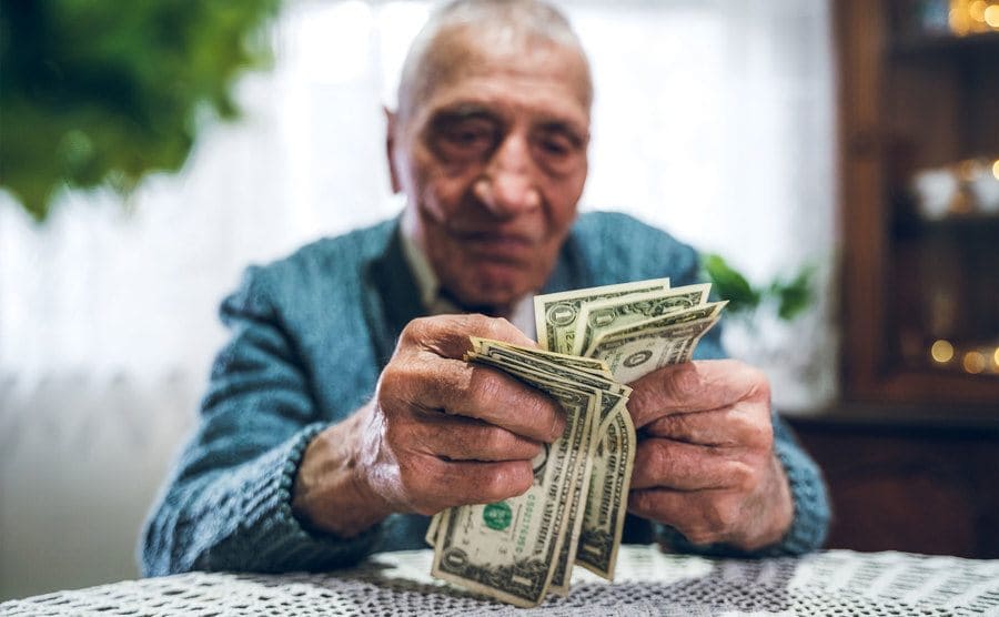 A senior man is counting US dollar bills. 