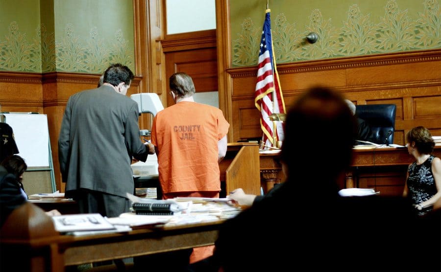 A man and his lawyer stand in court. 