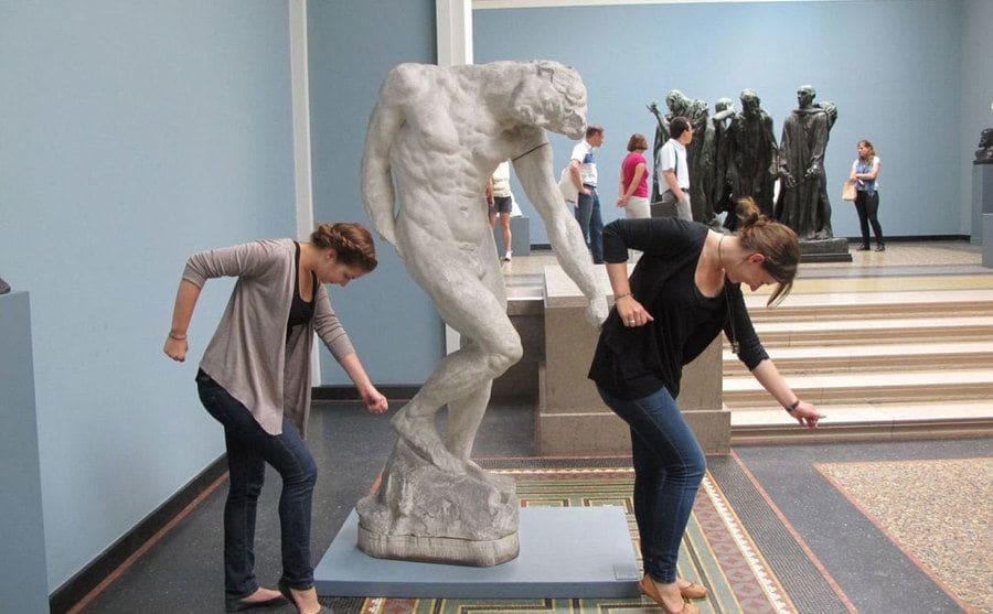 Dos chicas posan junto a una estatua, imitando su pose