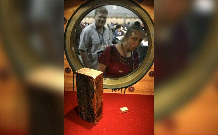Coin collector Darlene Corio, right, peers through a circular window at a gold ingot weighing more than 662 ounces, which was among two tons of California Gold Rush gold recovered from the shipwreck.