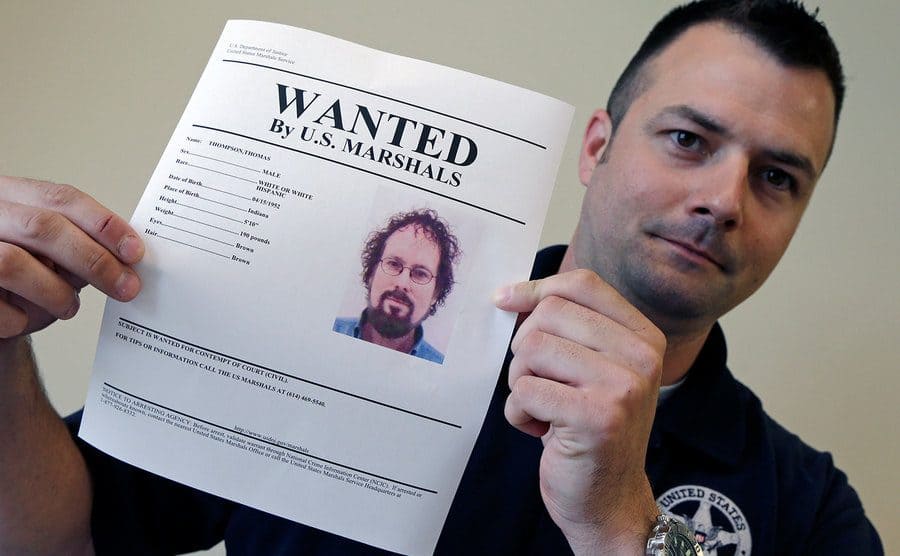 U.S. Marshal Brad Fleming displays a wanted poster for fugitive treasure hunter Tommy Thompson in Columbus, Ohio.