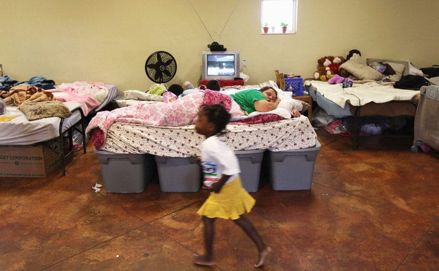 A homeless child runs past a homeless mother sleeping in a family shelter. 