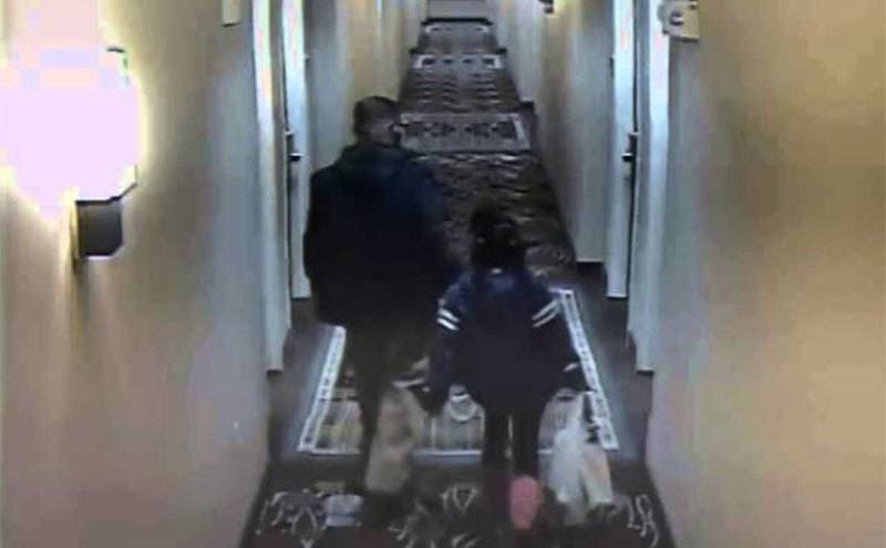 Relisha walking with a man in a hallway carrying shopping bags in a still from CCTV footage. 