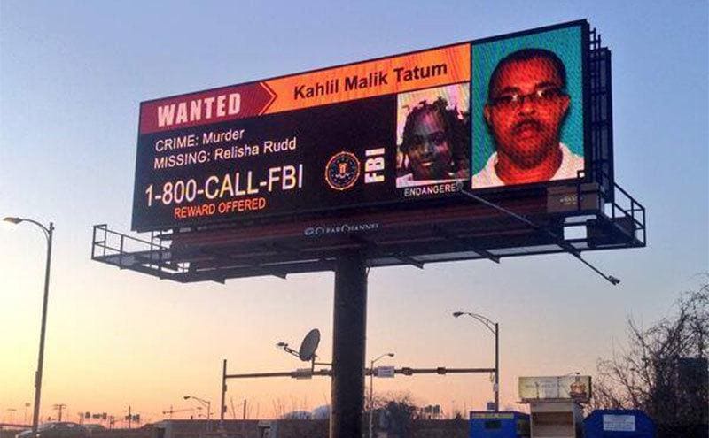 A wanted poster looking for Tatum and Relisha on a giant LED billboard. 