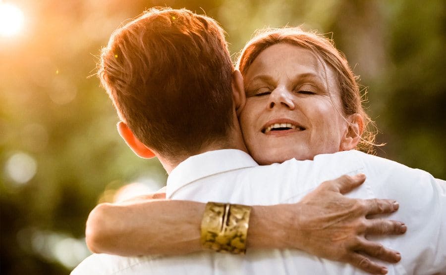 An older woman is embracing her long-lost son. 