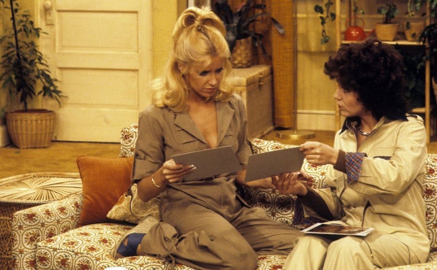 Suzanne Somers looking at photographs on the sofa with Joyce DeWitt 