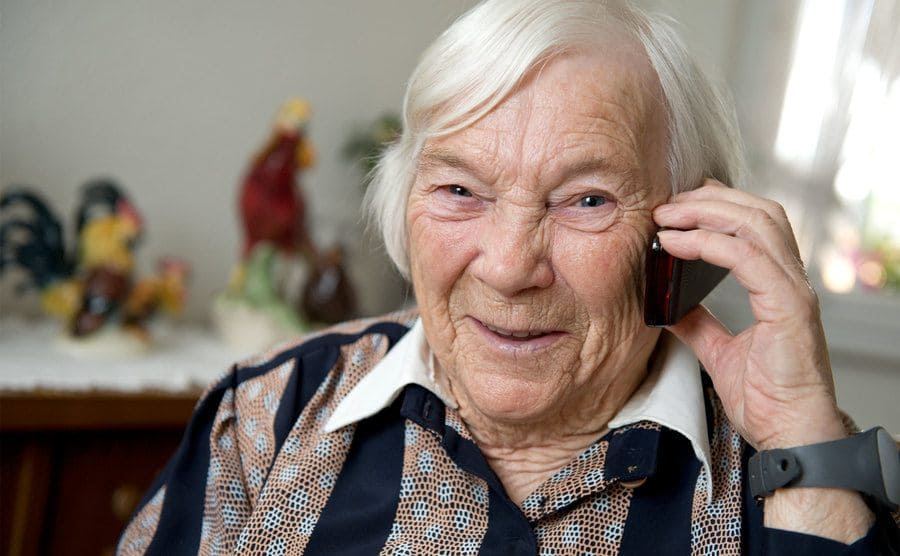 Female senior smiles into the camera as she talks on the phone.