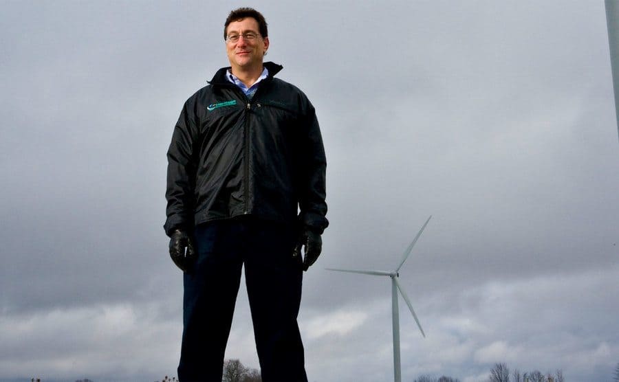 Marty Lagina is standing in front of wind turbines. 