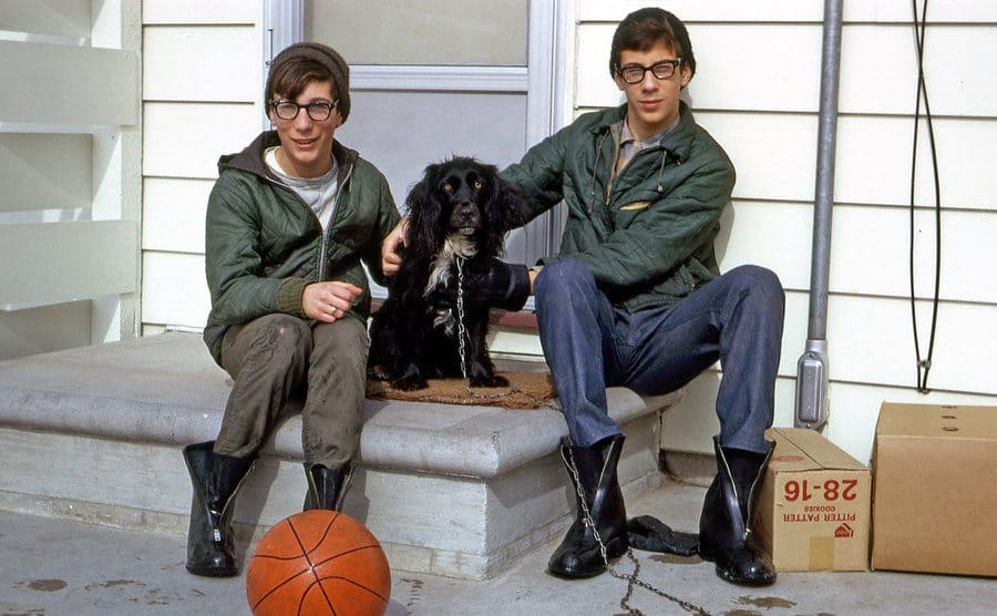 Rick and Marty as teenagers sitting on their front porch while petting their dog. 