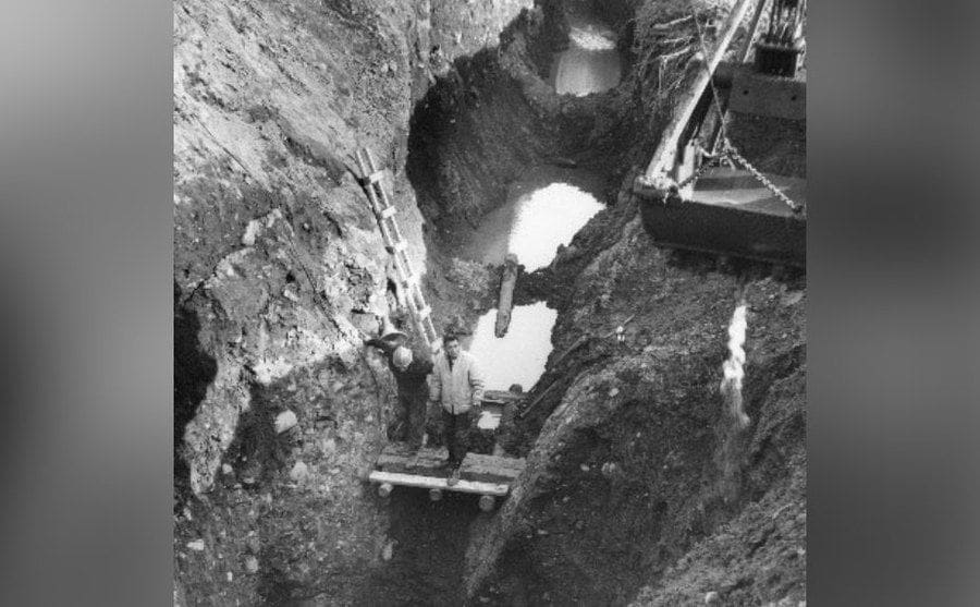Two men are standing at the bottom of the deep dugout ‘money pit’. 